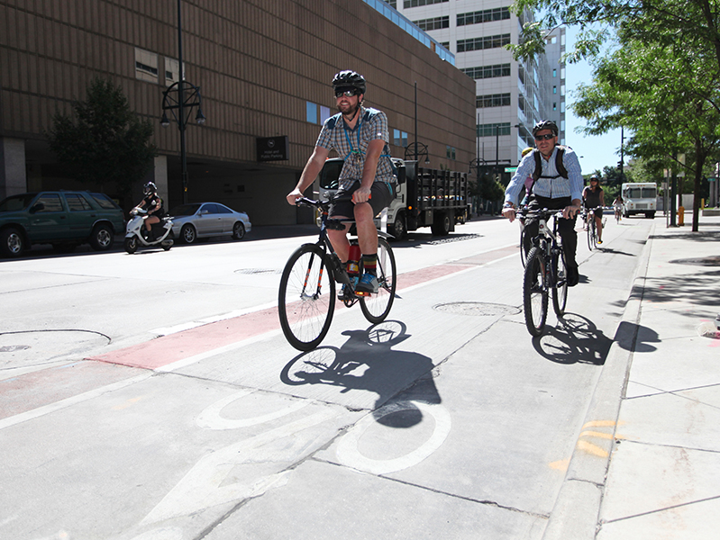 bicyclists in bike lane wearing helmets in Denver, CO