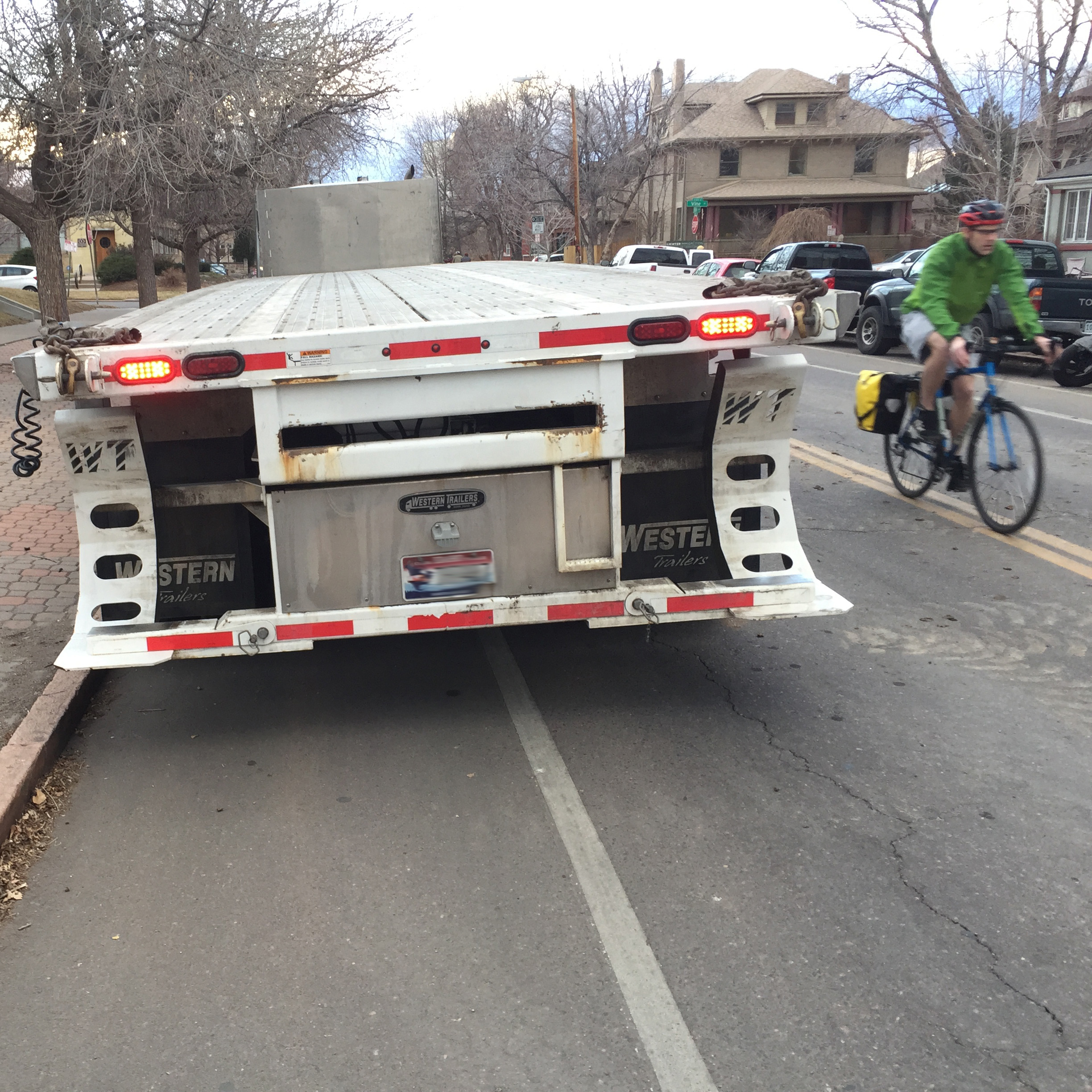 A person biking into the street because there is a large truck parked in a bike lane.