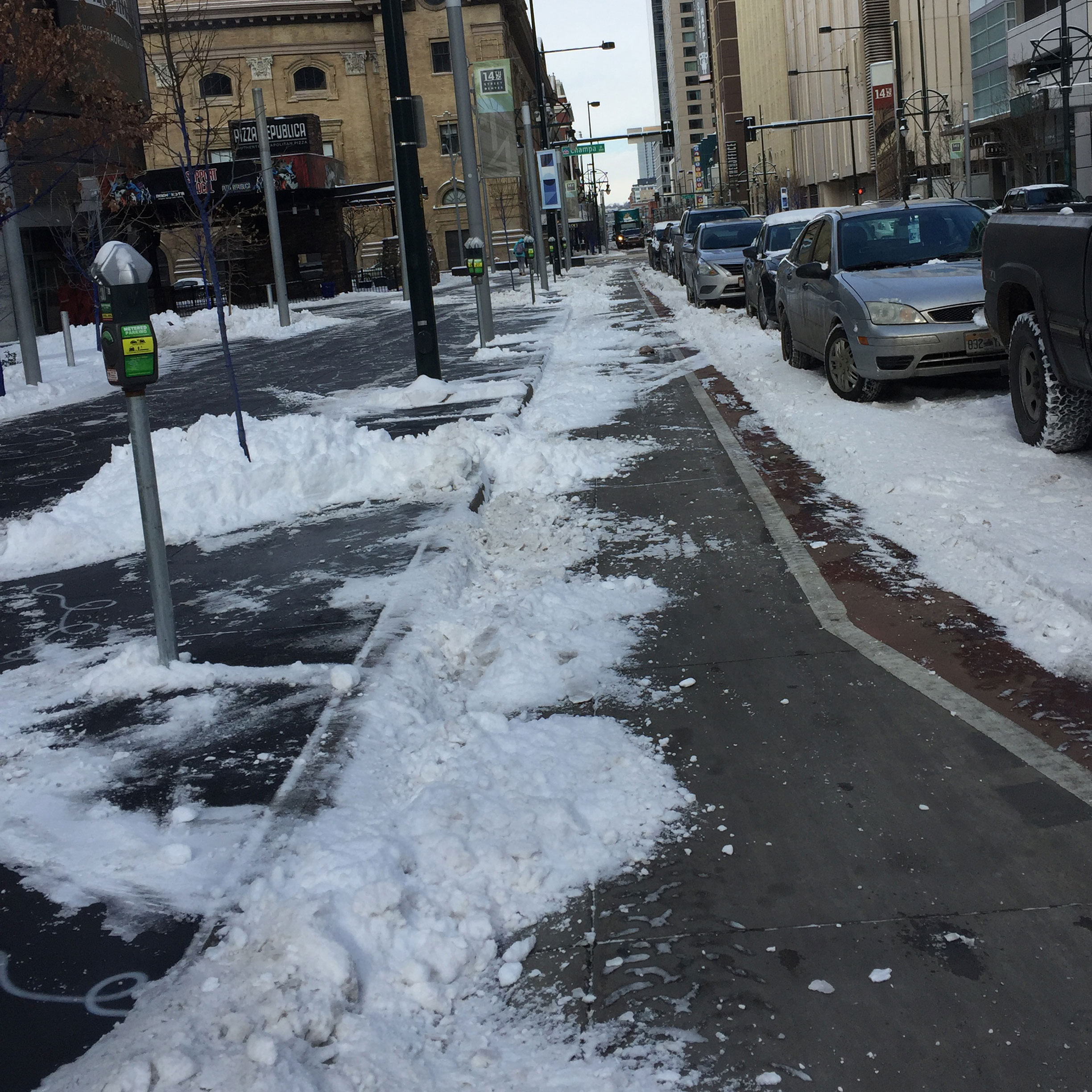 A bike lane with snow piles in it.