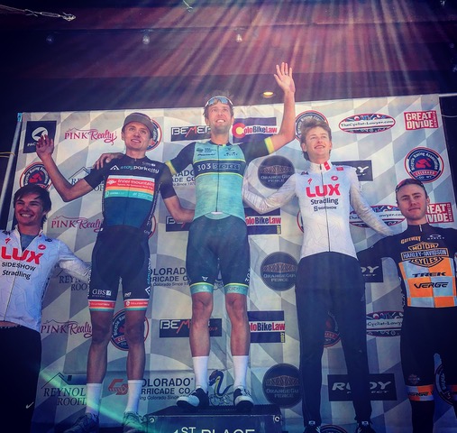 Chris Winn, Bicycle Colorado education team member, standing in the first place spot on a podium with four other competitors nearby.