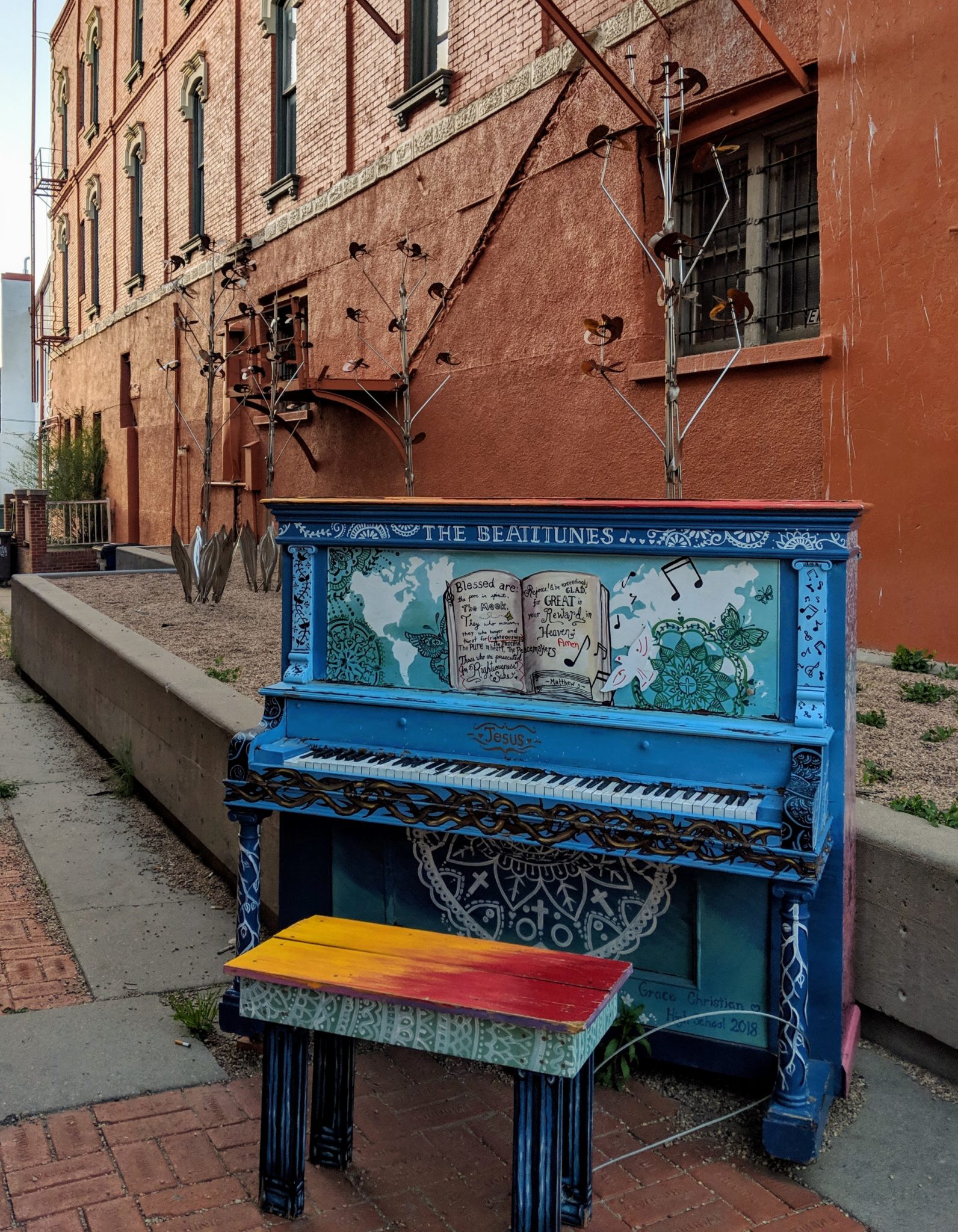 A painted and decorated piano in an alley.