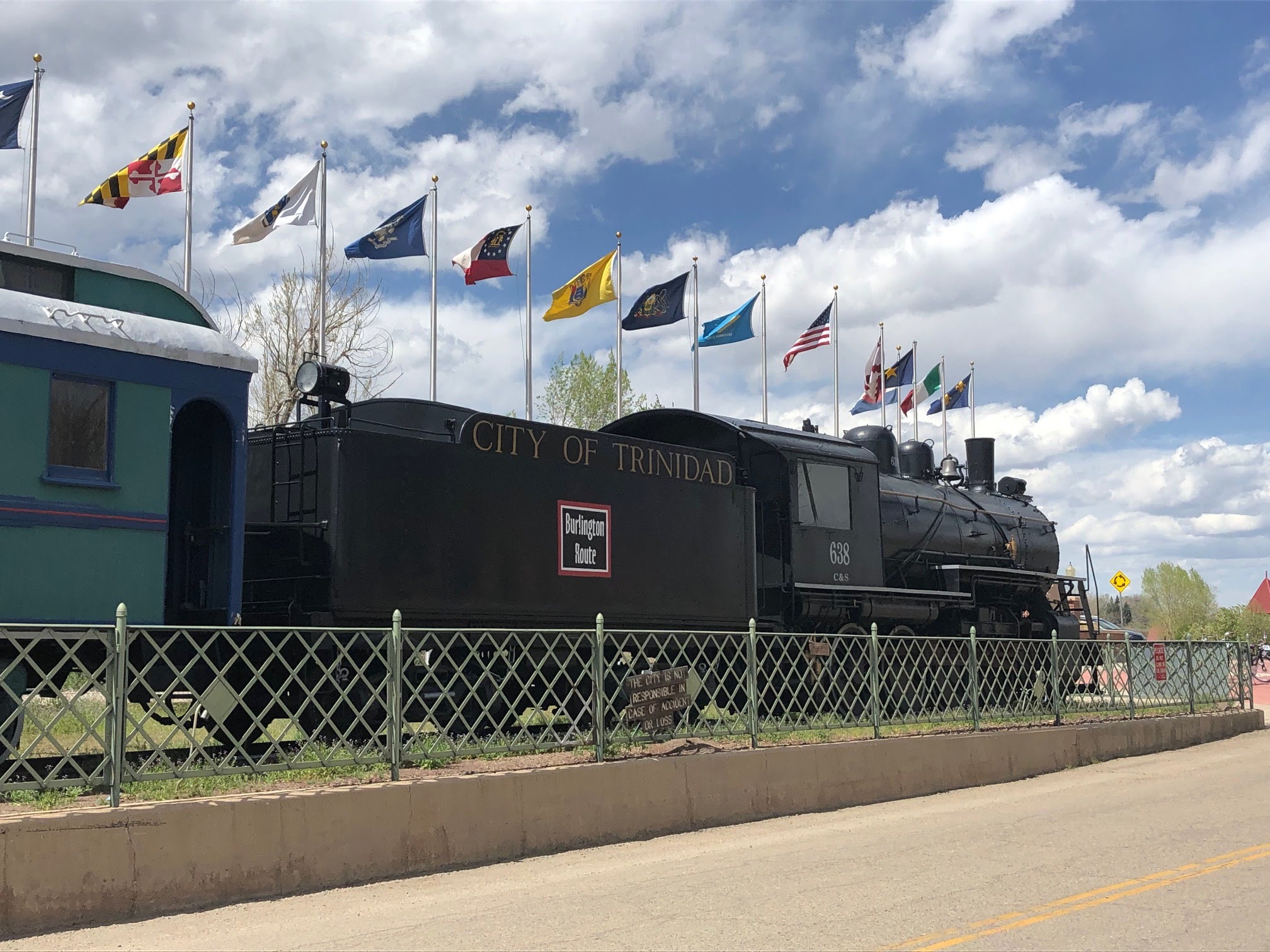 An old steam engine with flags mounted behind it.