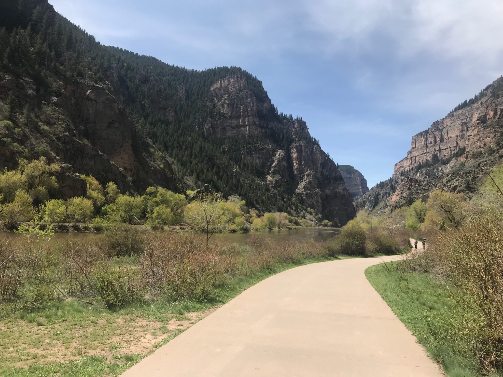 A paved trail alongside a river flowing through a canyon.