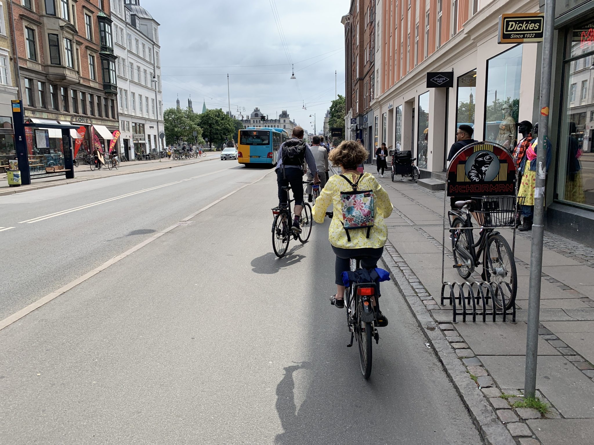 People riding bikes on a raised cycle track next to a street in Copenhagen.