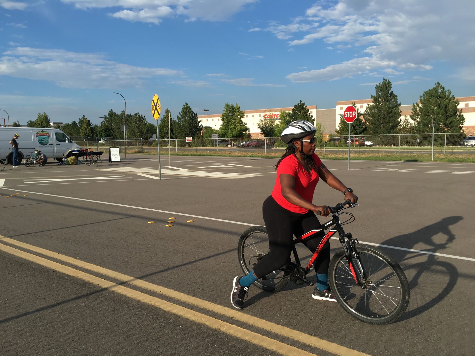 An adult learning to ride a bike in a parking lot and empty street.
