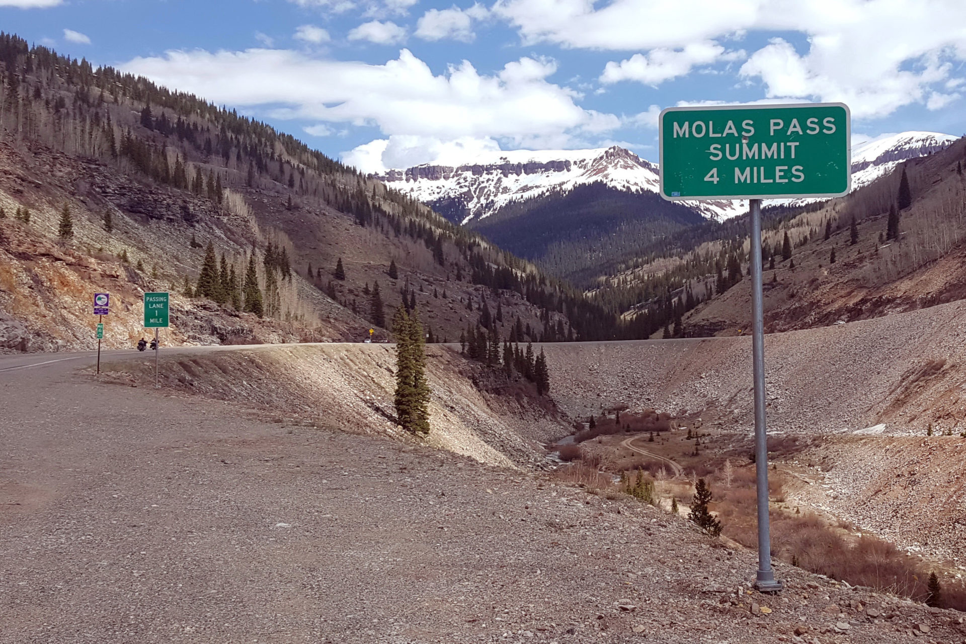 A sign on the side of a mountain road reading "Molas pass summit, 4 miles."