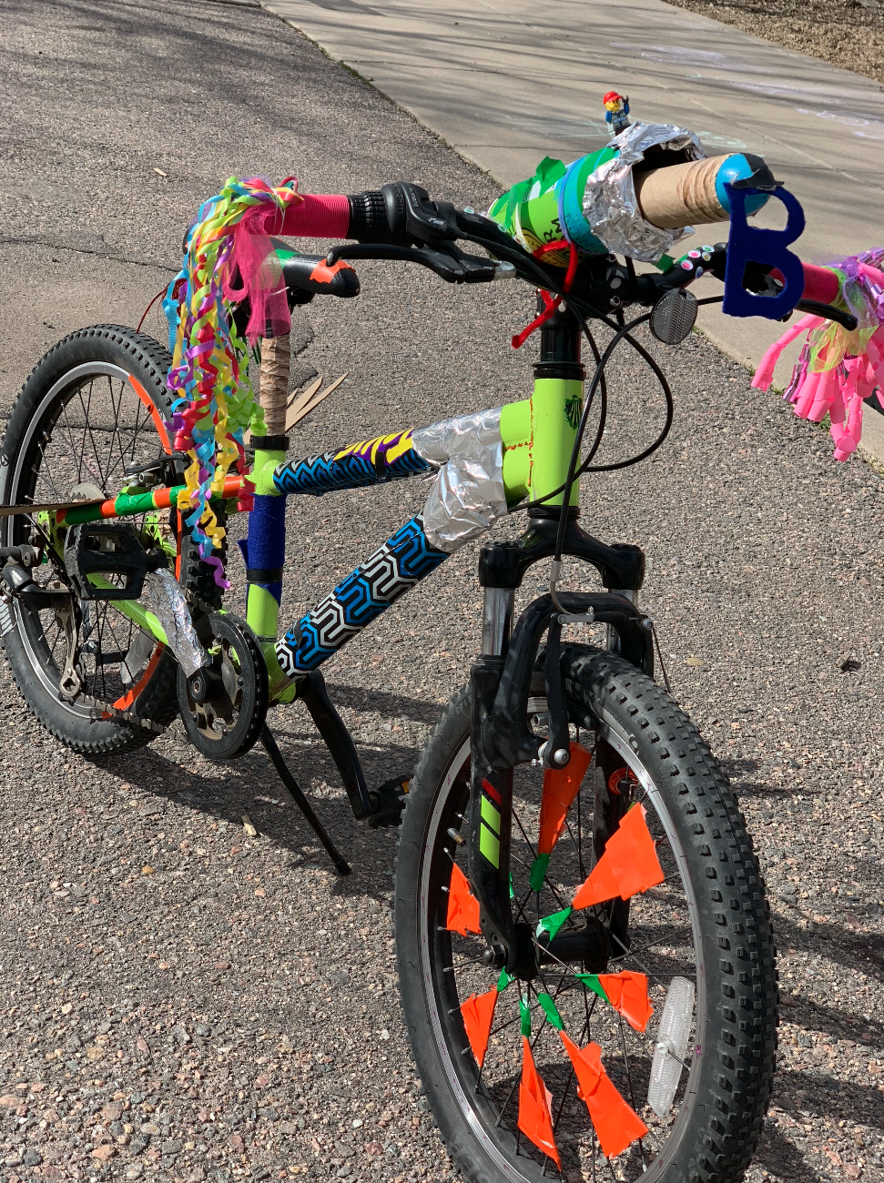 A small children's bike decorated with brightly colored streamers and tape.