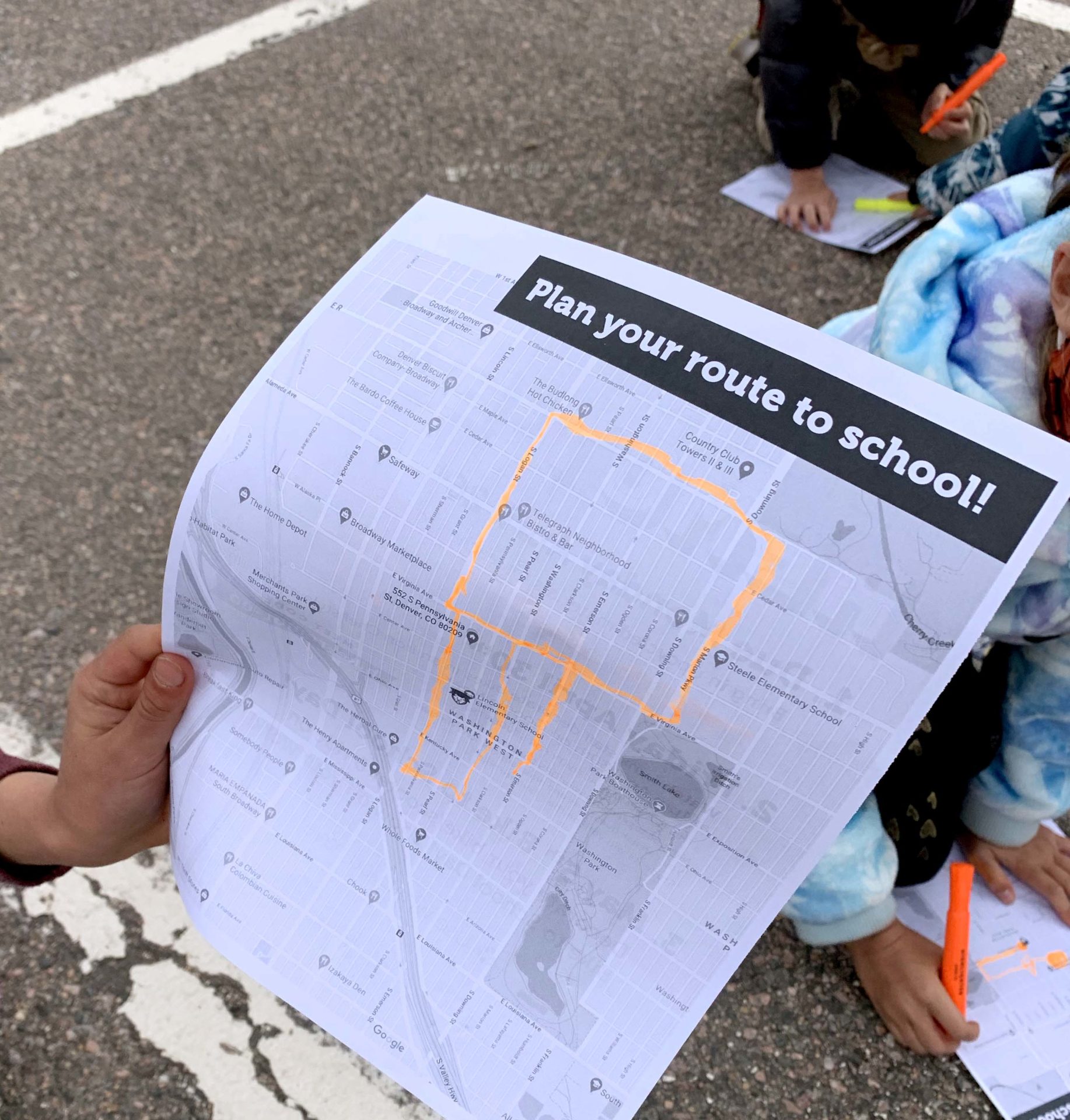 route_planning_9481 A hand holding a piece of paper that features a map with a route highlighted, and says "Plan your route to school!"