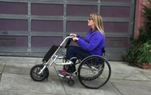 A person using a scooter attachment on their wheelchair rides to the left of the frame.