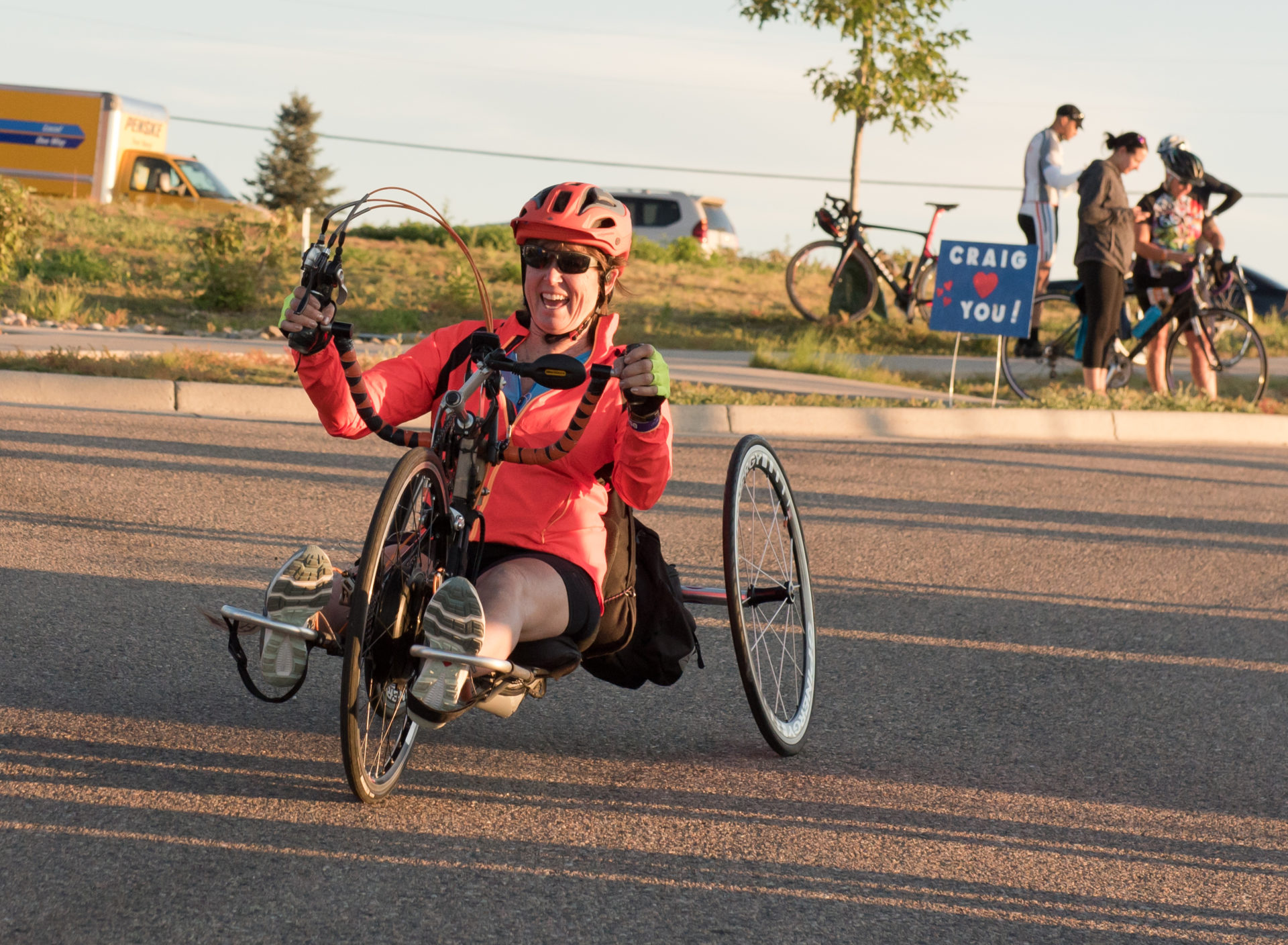 A person riding a recumbent trike rides on a paved road.
