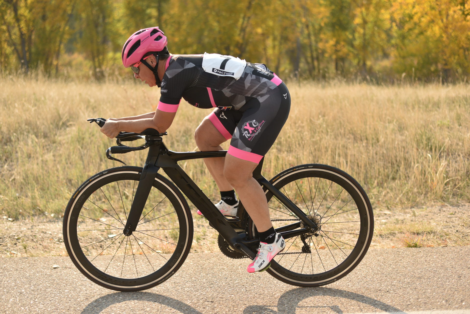 A person rides a road bike on a paved road toward the left of the frame.