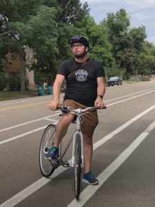 Person riding a commuter bike in Fort Collins with a Bicycle Colorado shirt