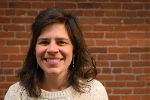 Portrait photo of woman standing in front of brick wall