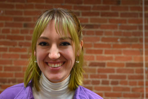 Portrait photo of woman standing in front of brick wall