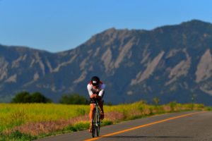 a lone bicyclist makes their way down a road with the infamous Boulder flat irons behind them