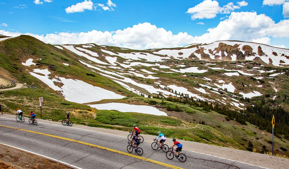 a group of bicyclists ride along a road in the mountains during the Triple Bypass.