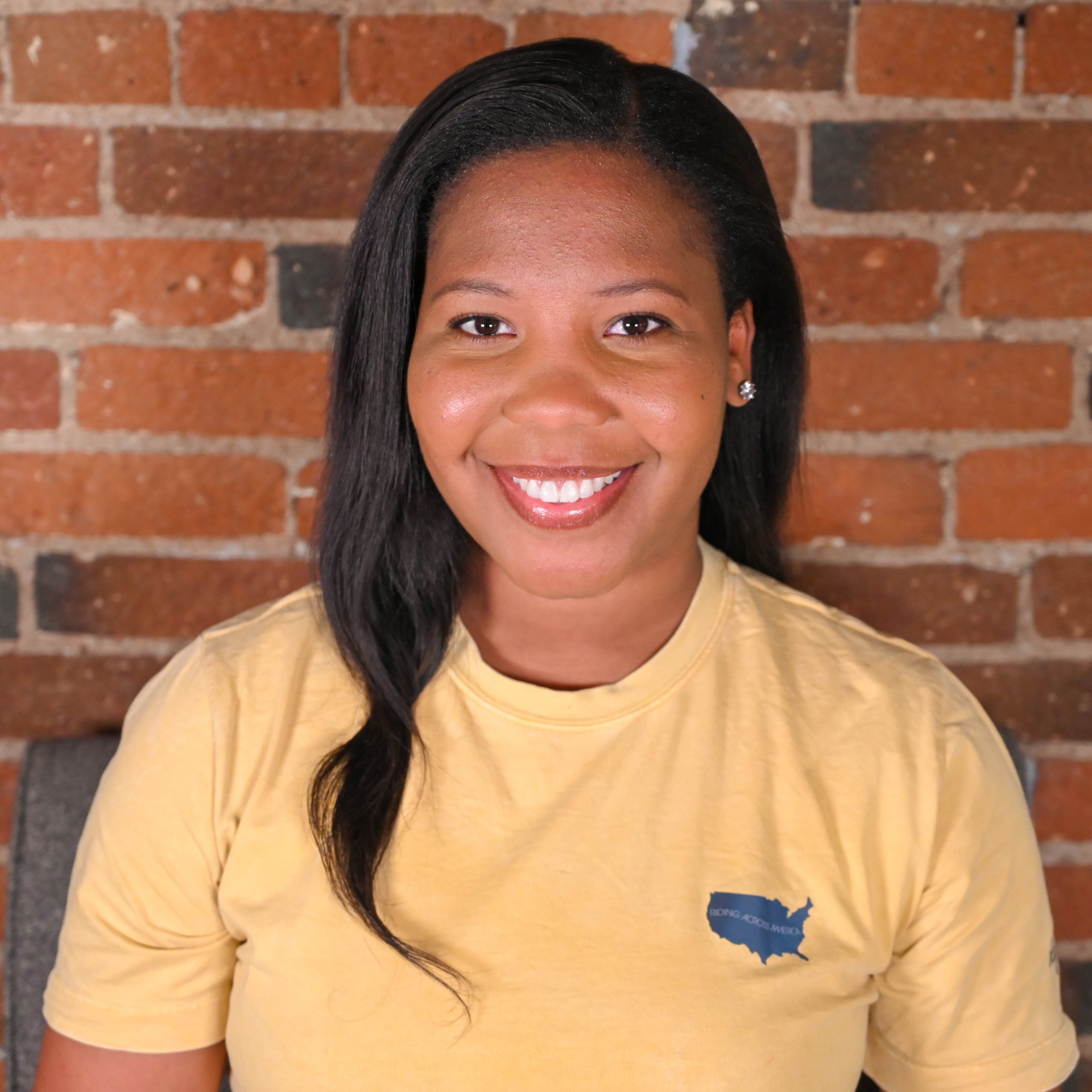 A Black woman wearing a yellow shirt photographed from the chest up.