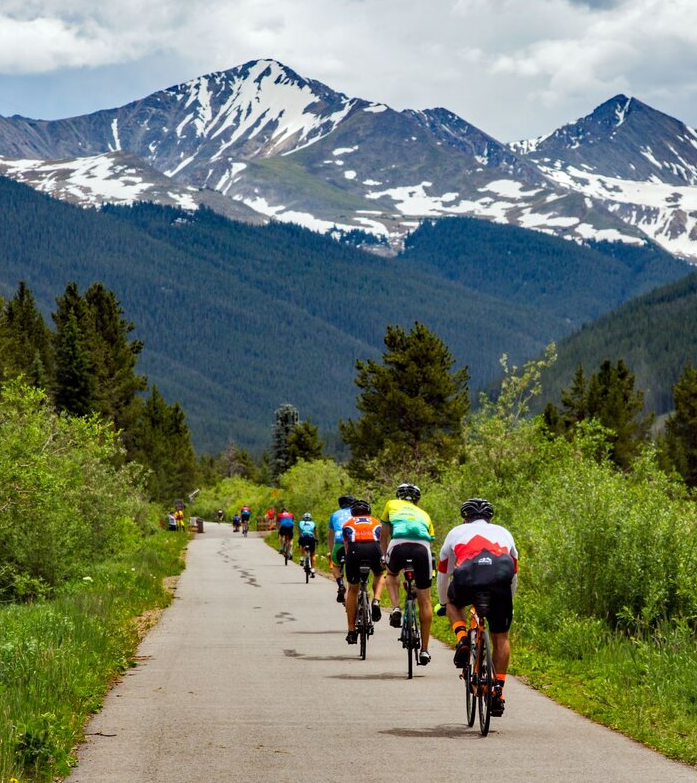 A line of bicyclists riding down a trail in the mountains during the Triple Bypass.