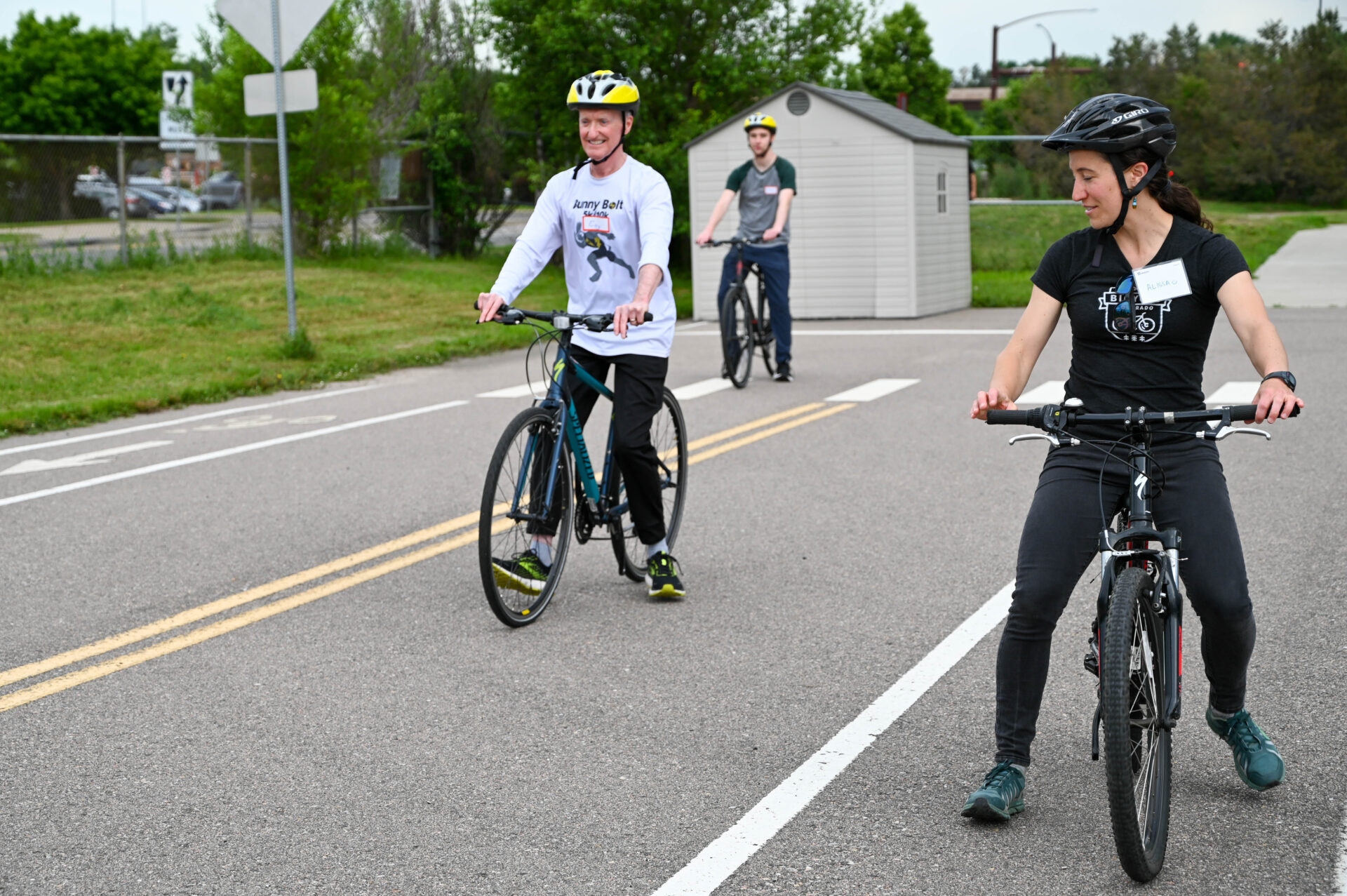 An older adult learning to ride a bike with a volunteer alongside, encouraging him.