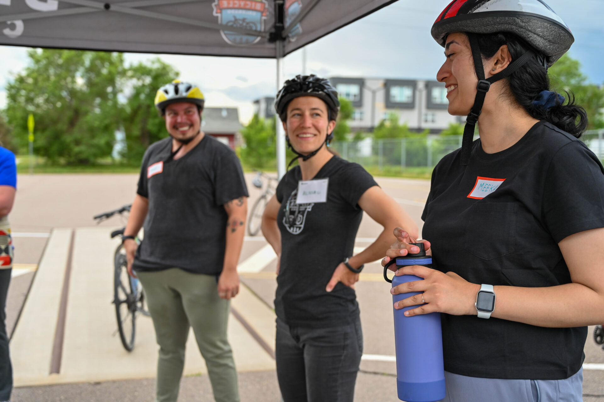 Three people smiling, wearing helmets and looking at each other.