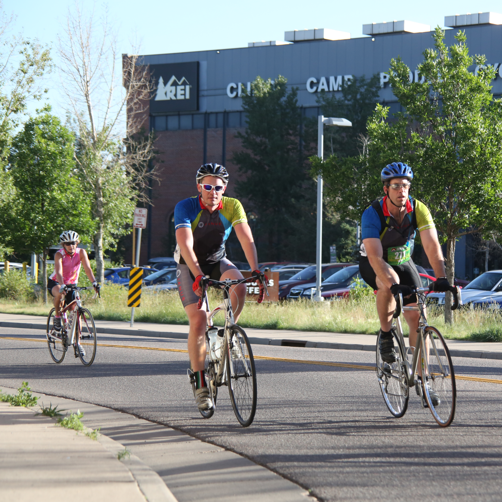 a group of people on bikes rides in front of REI in Denver, CO.