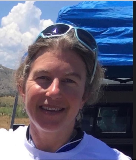 Andrea Koenig in front of a blue tent, blue sky, and white puffy cloud