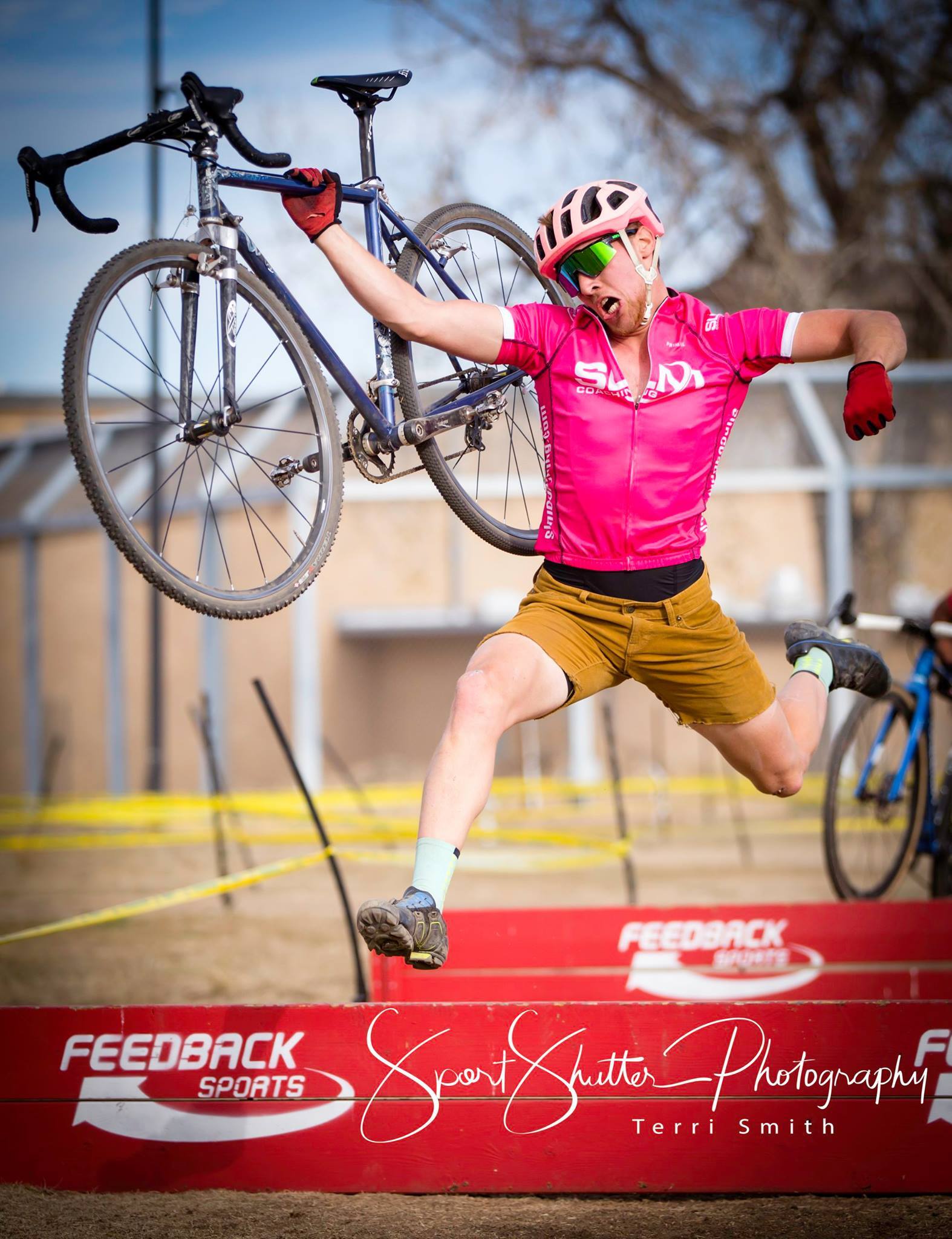 Solo adult cyclocross rider carrying bike across obstacle
